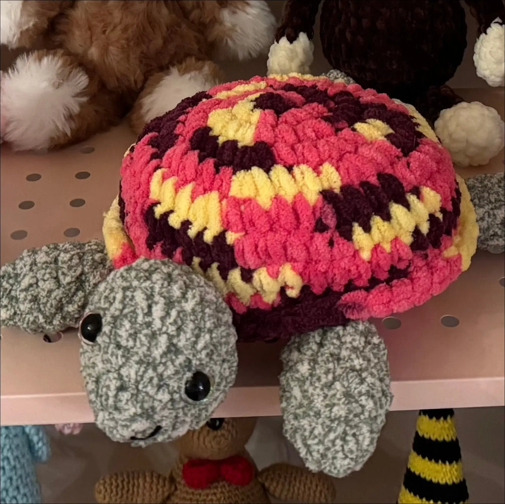 Crocheted turtle with a colorful shell on a pegboard