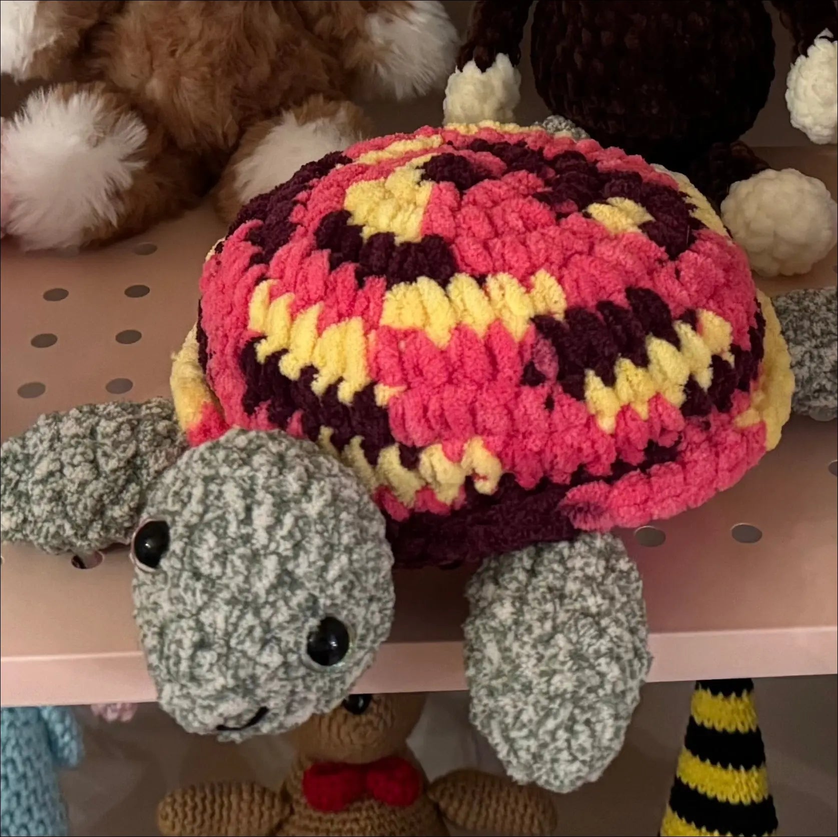 Crocheted turtle with a colorful shell on a pegboard