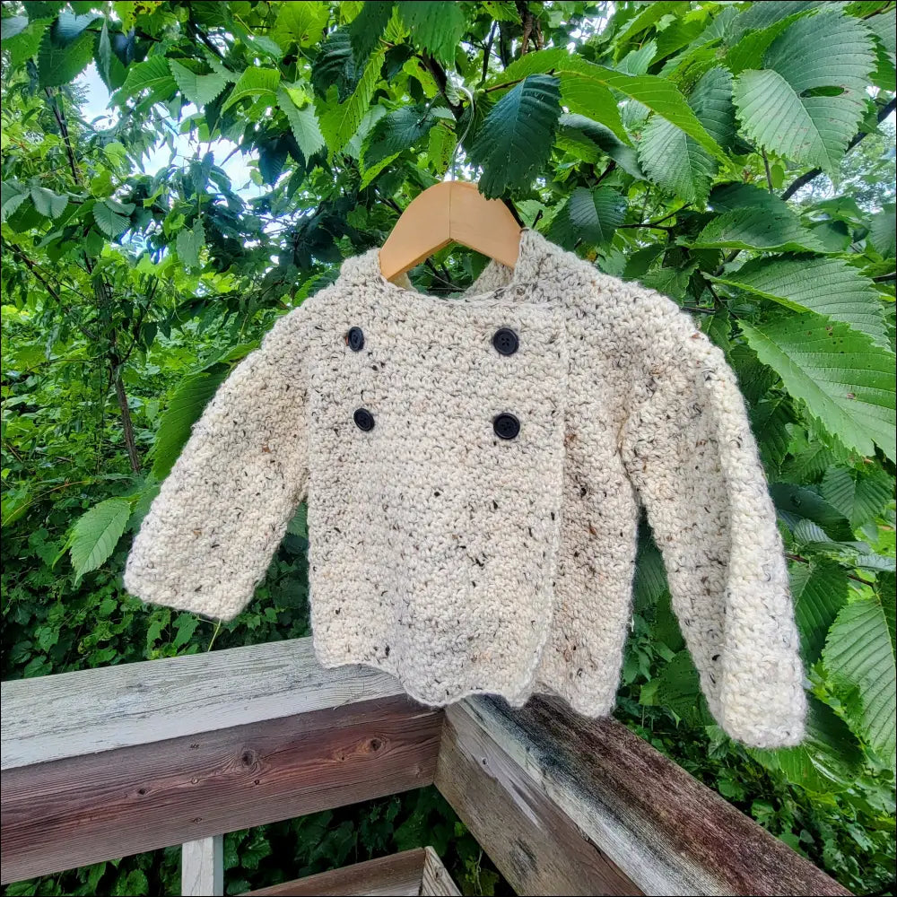 Fluffy beige cozy tweed sweater with wooden buttons hanging on a wooden hanger